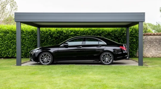 Voiture stationnée sous un carport aluminium gris anthracite dans un jardin résidentiel